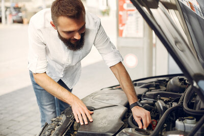 Kontrolle eines Autos mit Motorschaden für den Verkauf Ein Mann kontrolliert, ob er sein Auto mit Motorschaden verkaufen kann oder ob es noch repariert werden muss.